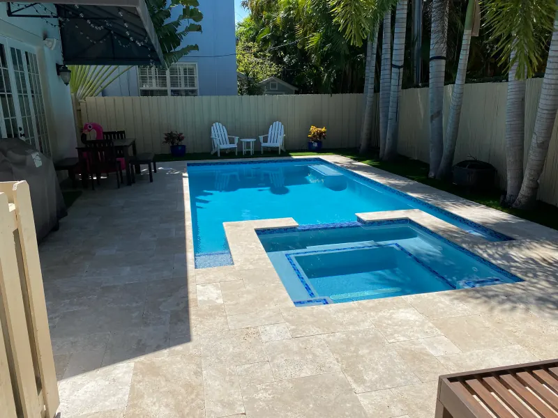 Rectangular pool with an attached spa and travertine deck