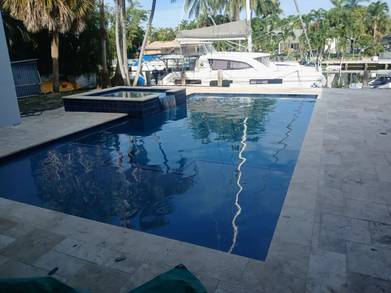 Dark-finish pool with a raised spa beside the boat dock