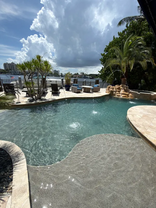 Beach-entry pool with bubblers and a rock waterfall on the water