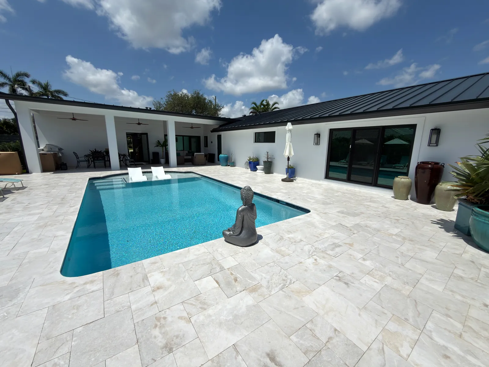 Pool with in-pool loungers on the sun shelf and a wide marble deck