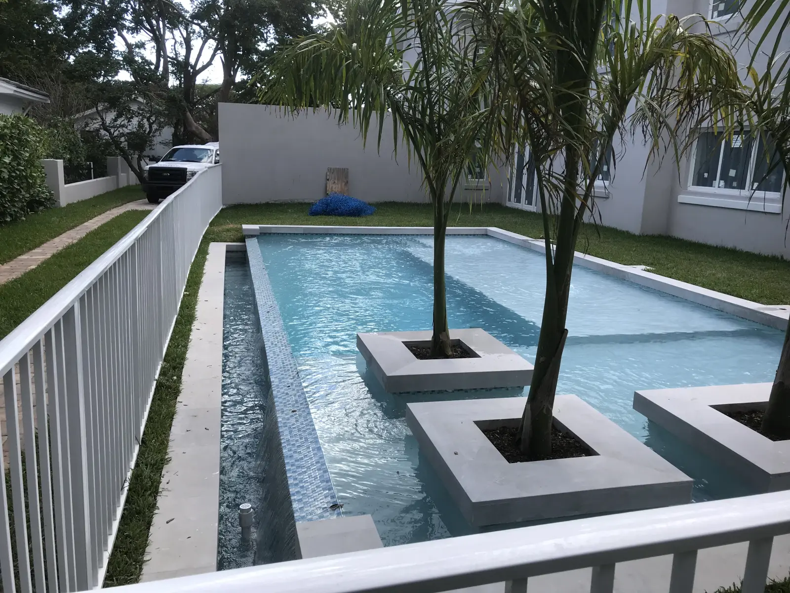 Long modern pool with palm tree planter islands and a tiled lap lane