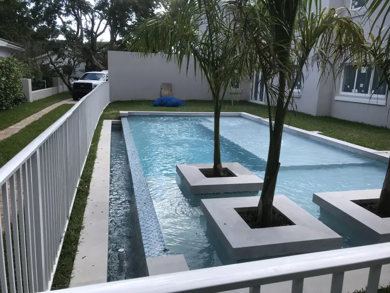 Long modern pool with palm tree planter islands and a tiled lap lane