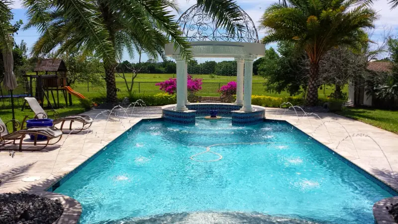 Rectangular pool with a white gazebo fountain and deck jets