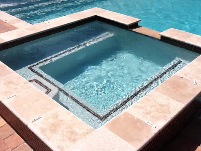 Spa with tile banding and travertine coping