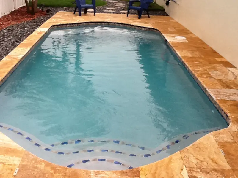 Pool with rounded ends, mosaic steps and travertine deck