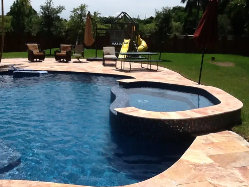 Freeform pool with raised spa and travertine deck