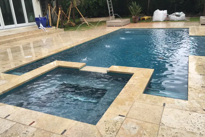 Geometric pool with attached spa and travertine deck