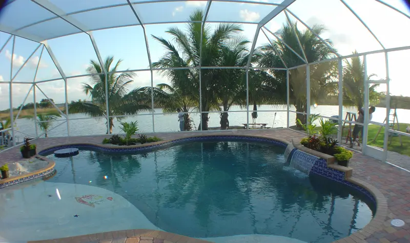 Screened freeform pool with planter islands