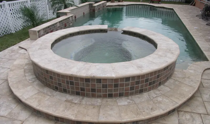 Round raised spa with tile and travertine