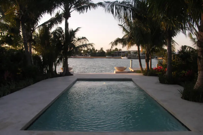 Waterfront pool at dusk with travertine deck